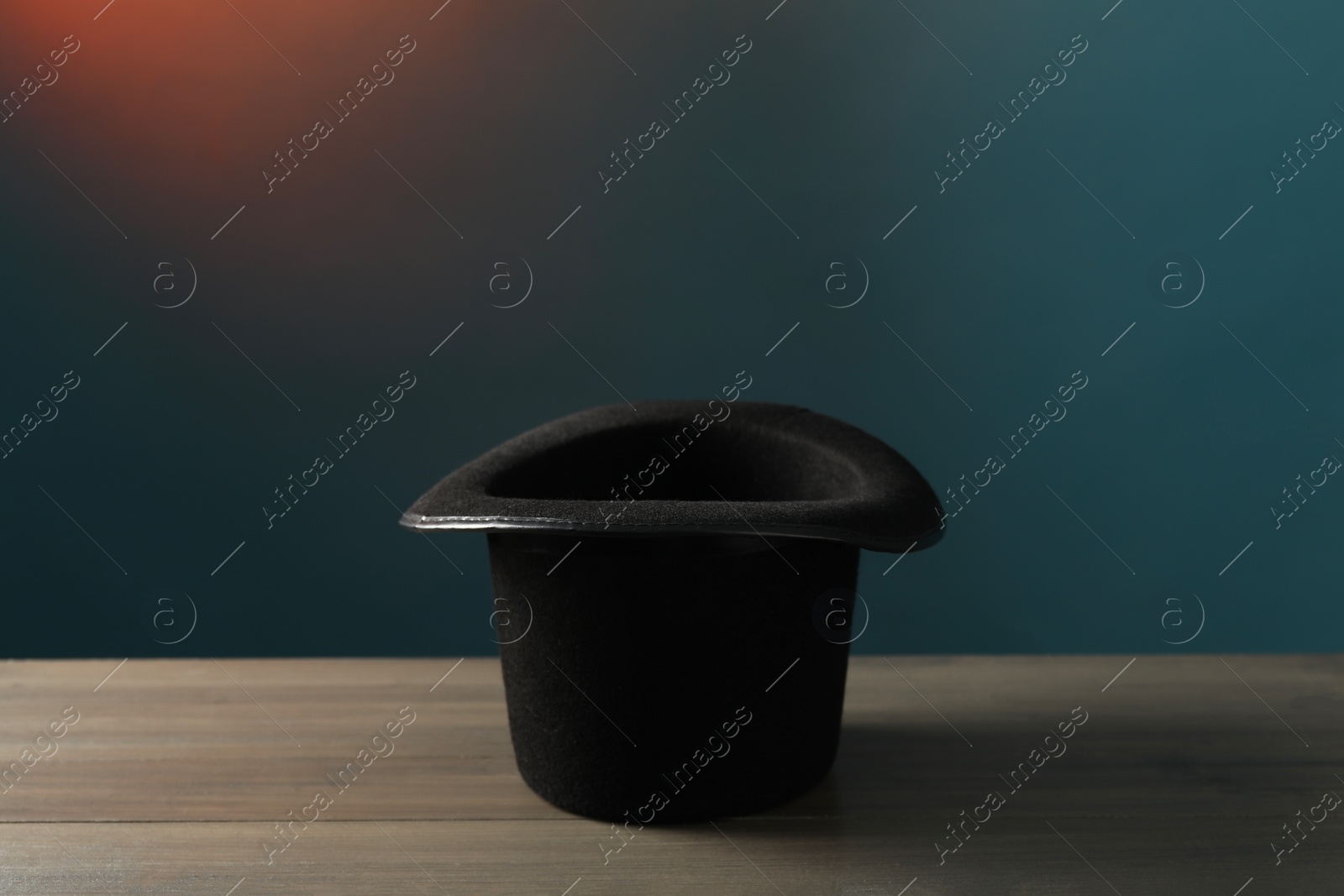 Photo of Magician's hat on wooden table against dark background