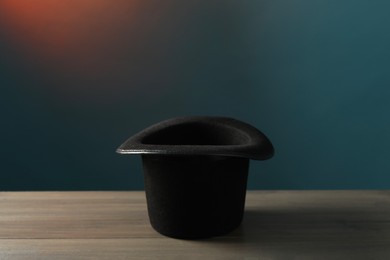 Photo of Magician's hat on wooden table against dark background