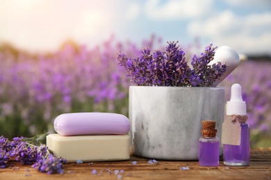 Photo of Composition with fresh lavender flowers and cosmetic products on wooden table outdoors, closeup