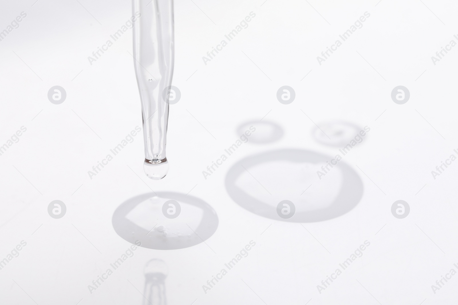 Photo of Glass pipette and transparent liquid on white background, closeup