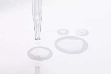 Glass pipette and transparent liquid on white background, closeup