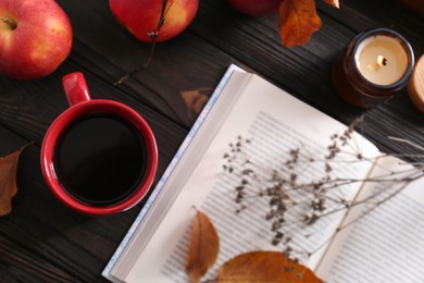 Cup of hot drink, book and ripe apples on wooden table, flat lay. Cozy autumn atmosphere