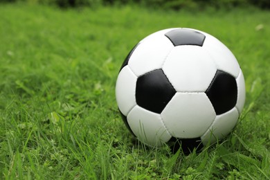 Photo of Football ball on green grass outdoors, space for text