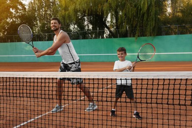 Father with his son playing tennis on court