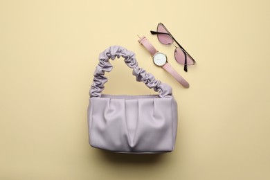 Stylish woman's bag, watch and sunglasses on beige background, flat lay