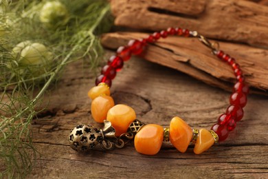 Photo of Stylish presentation of beautiful bracelet with gemstones on wooden table, closeup