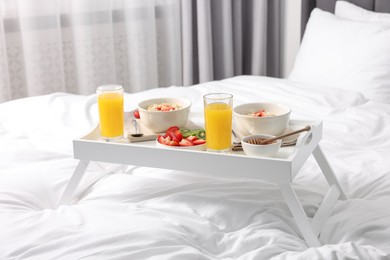 Photo of Tray with tasty breakfast on bed at home
