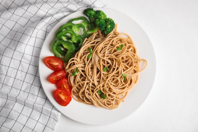 Photo of Tasty buckwheat noodles with fresh vegetables served on white table, flat lay