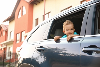 Photo of Happy little kid looking from family car outdoors