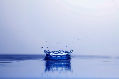 Splash of clear water with drops on light background, closeup