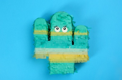 Photo of Bright cactus pinata on light blue background, top view