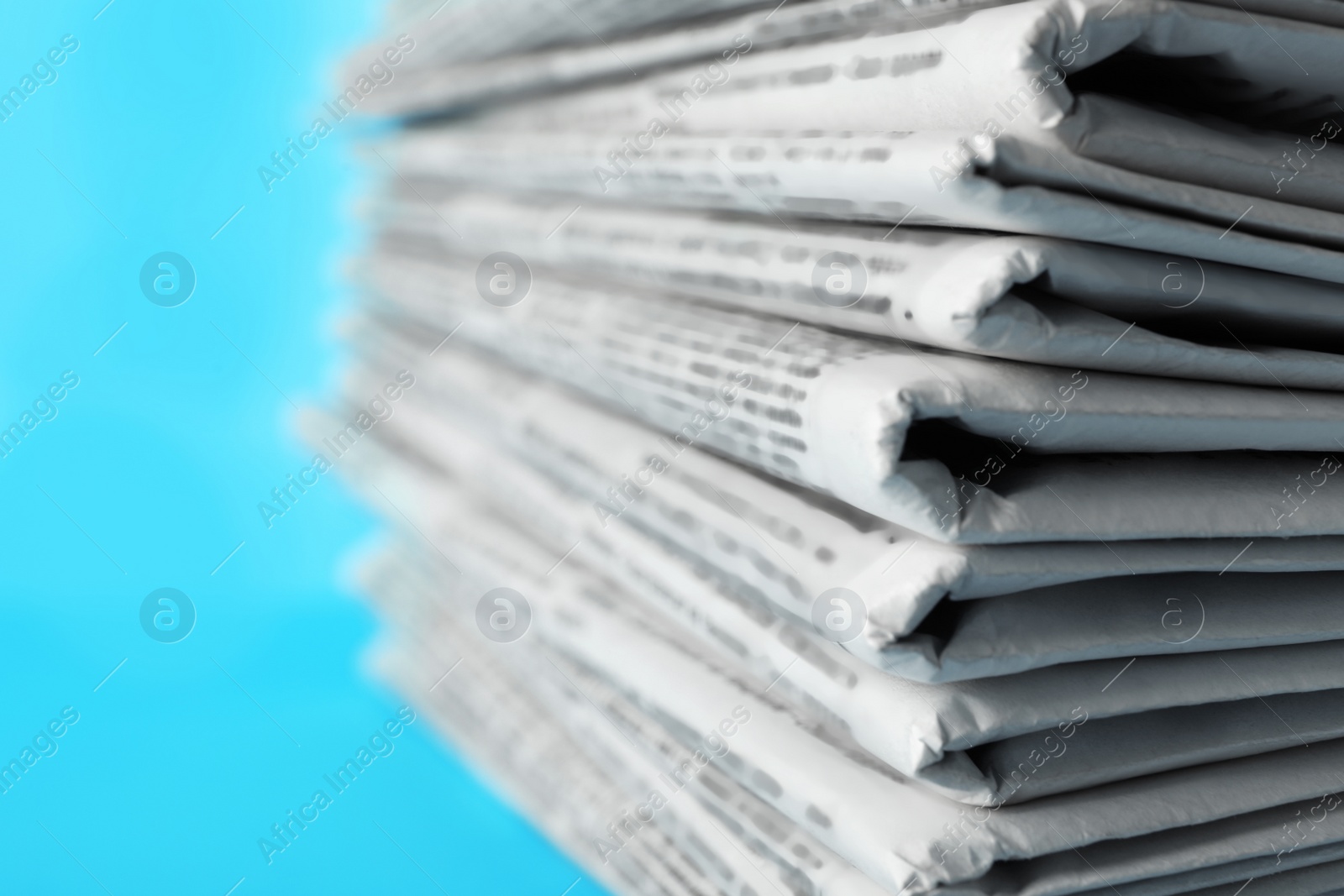 Photo of Stack of newspapers on light blue background, closeup. Journalist's work