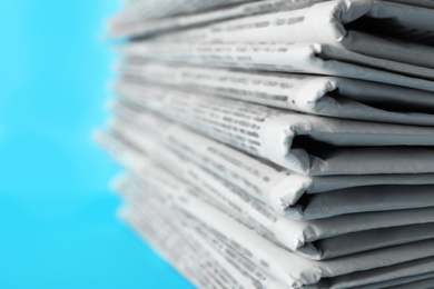 Photo of Stack of newspapers on light blue background, closeup. Journalist's work