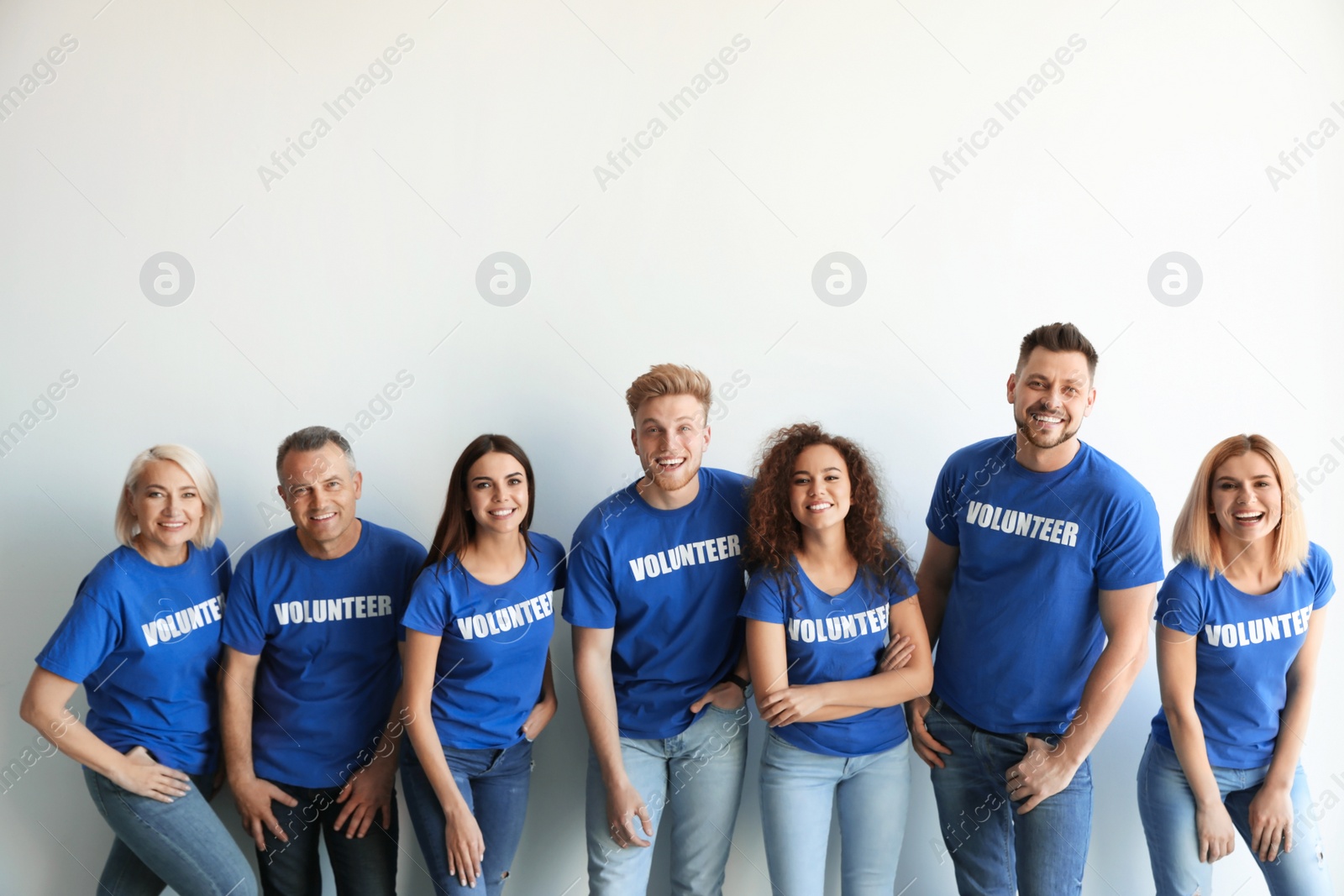 Photo of Team of volunteers in uniform on light background