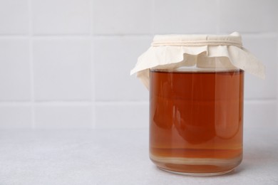 Tasty kombucha in glass jar on white table, space for text