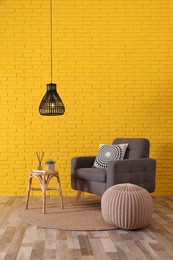 Photo of Stylish beige pouf, armchair and small table in room