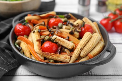 Photo of Tasty roasted baby corn with tomatoes, capers and mushrooms on white wooden table, closeup