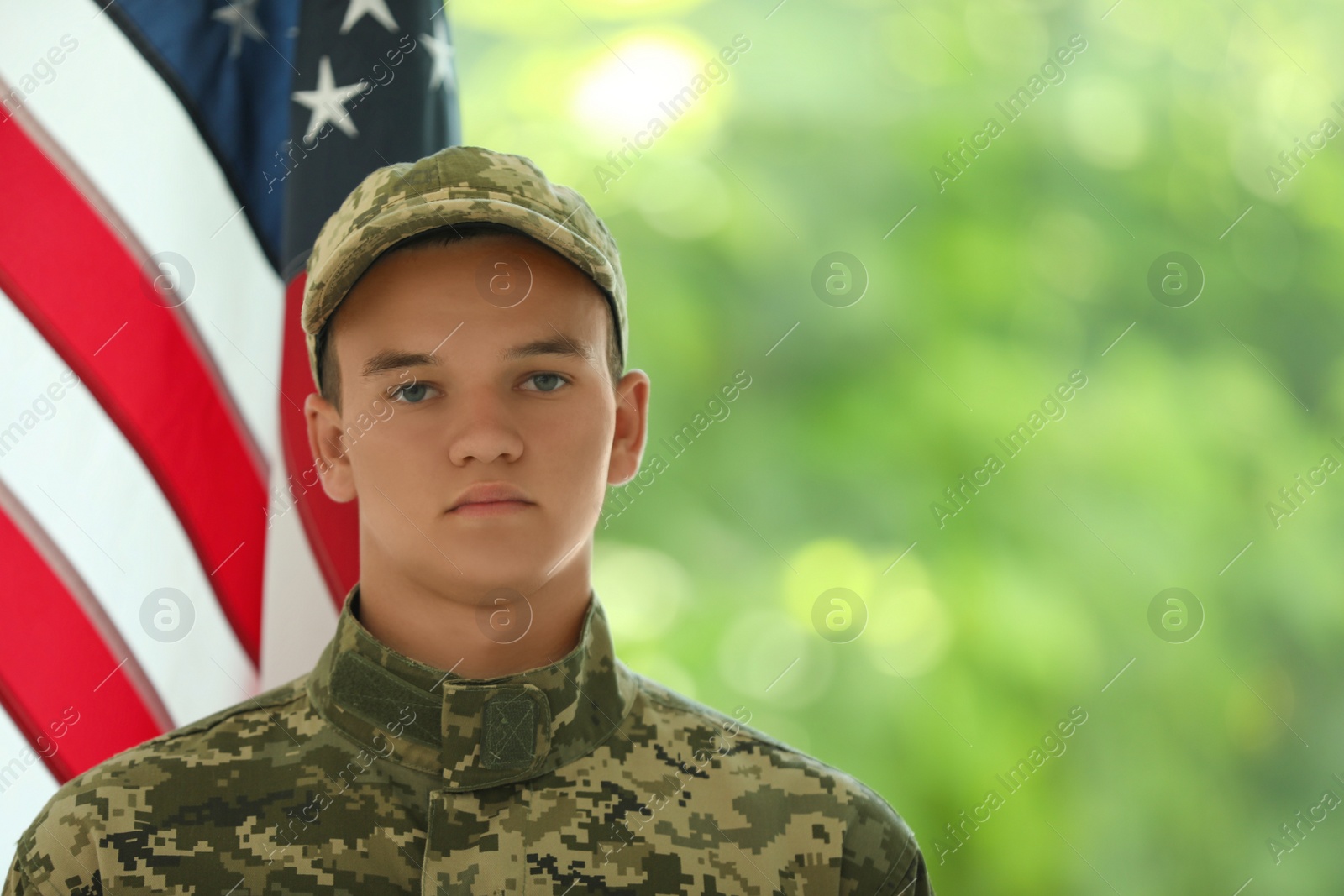 Photo of Male soldier in uniform near USA flag outdoors. Space for text