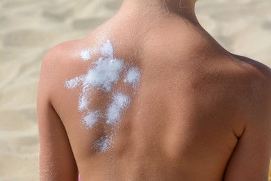 Photo of Child with sunscreen on back at beach, closeup