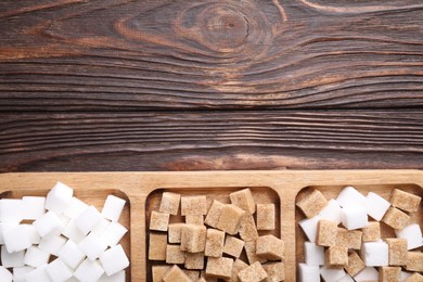 Tray with brown and white sugar cubes on wooden table, top view. Space for text