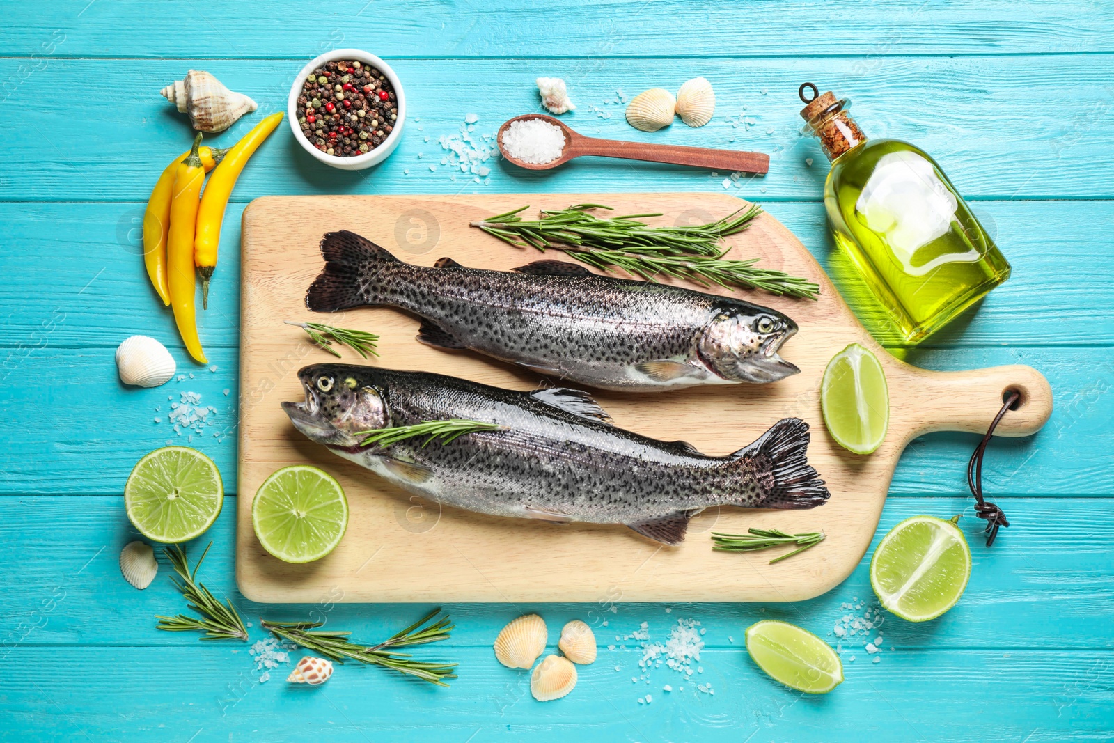 Photo of Flat lay composition with raw cutthroat trout fish on light blue wooden table