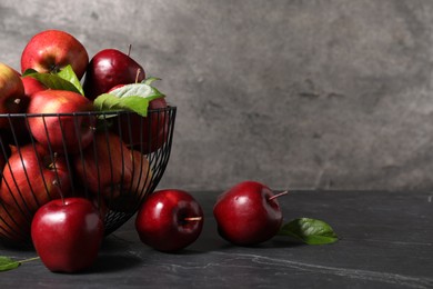 Photo of Fresh red apples and leaves on dark grey table. Space for text