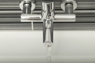 Photo of Water flowing from bath tap installed on black and white wall, above view