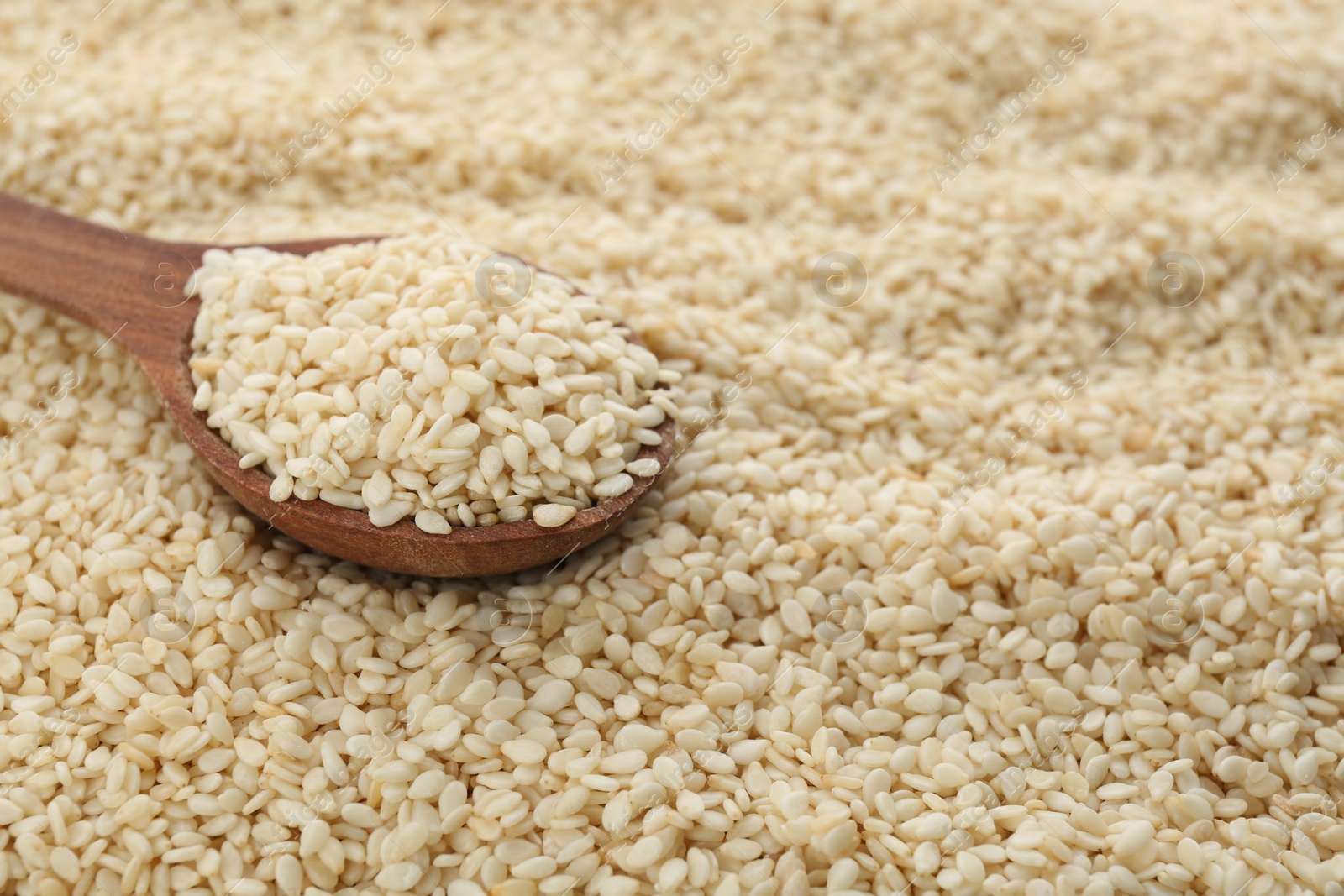 Photo of Wooden spoon on pile of white sesame seeds. Space for text