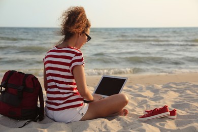 Photo of African American woman working on laptop at beach
