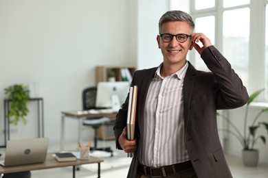 Happy man with notebooks in office, space for text