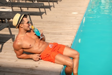 Photo of Young man with cocktail near pool on sunny day
