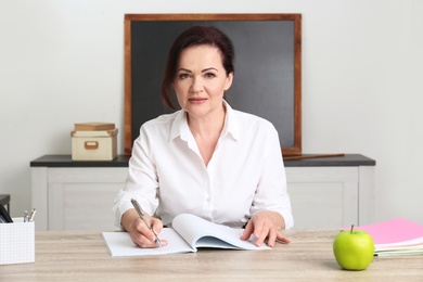 Photo of Portrait of female teacher sitting at table in classroom