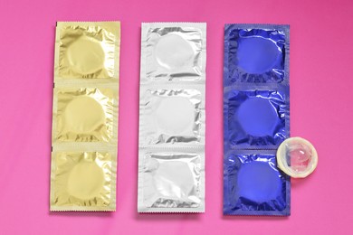 Unpacked condom and packages on pink background, flat lay. Safe sex
