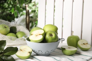 Photo of Fresh green apples with water drops and leaves on white table, closeup