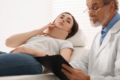 Photo of Orthopedist examining patient with injured neck in clinic