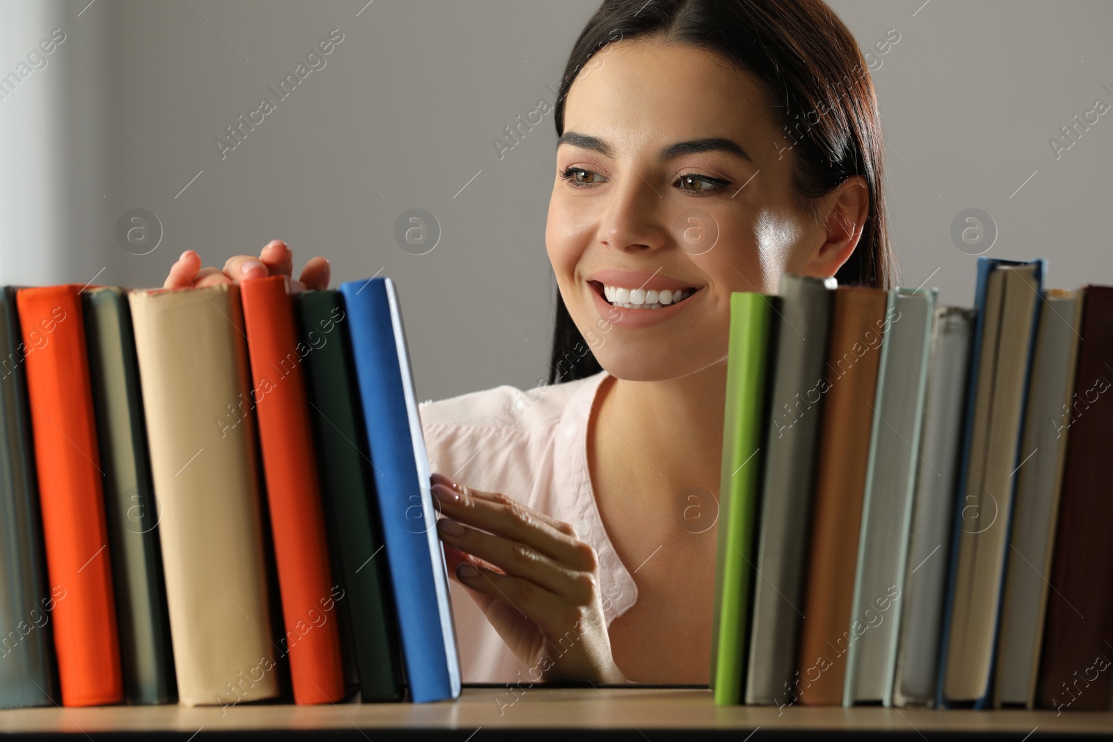Photo of Woman searching for book on shelf in library