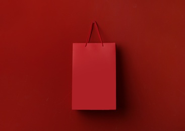 Photo of Paper shopping bag hanging on red background