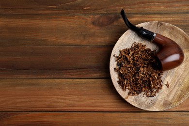 Photo of Board with smoking pipe and dry tobacco on wooden table, top view. Space for text