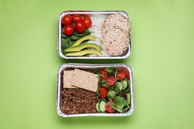 Photo of Containers with different fresh products on light green background, flat lay