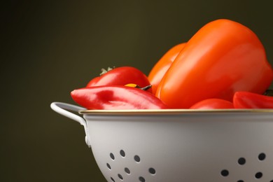 Photo of Colander with fresh vegetables on olive background, closeup