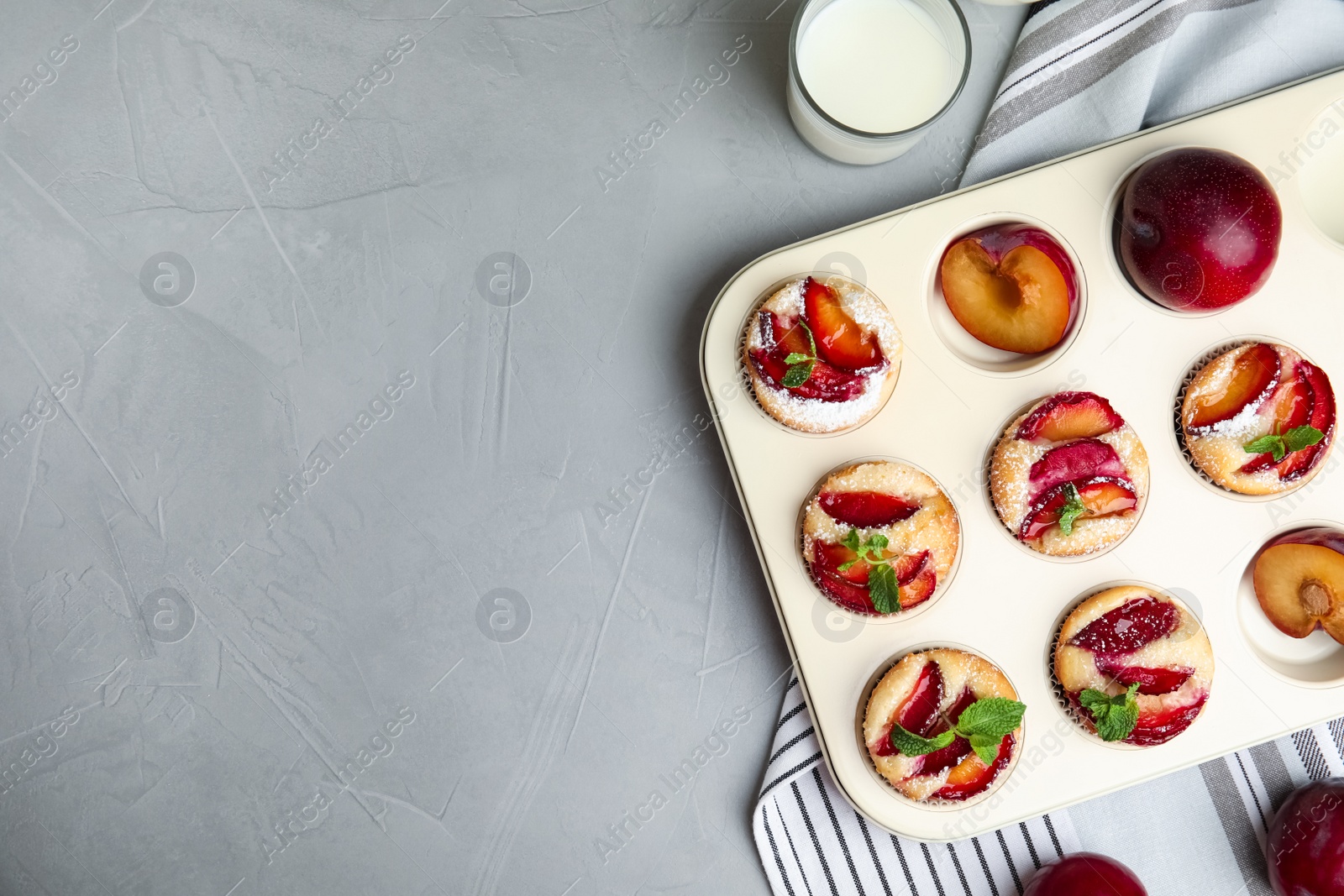 Photo of Delicious cupcakes with plums in baking pan, flat lay. Space for text