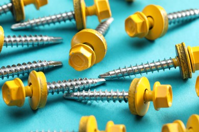 Yellow self-tapping screws on light blue background, closeup