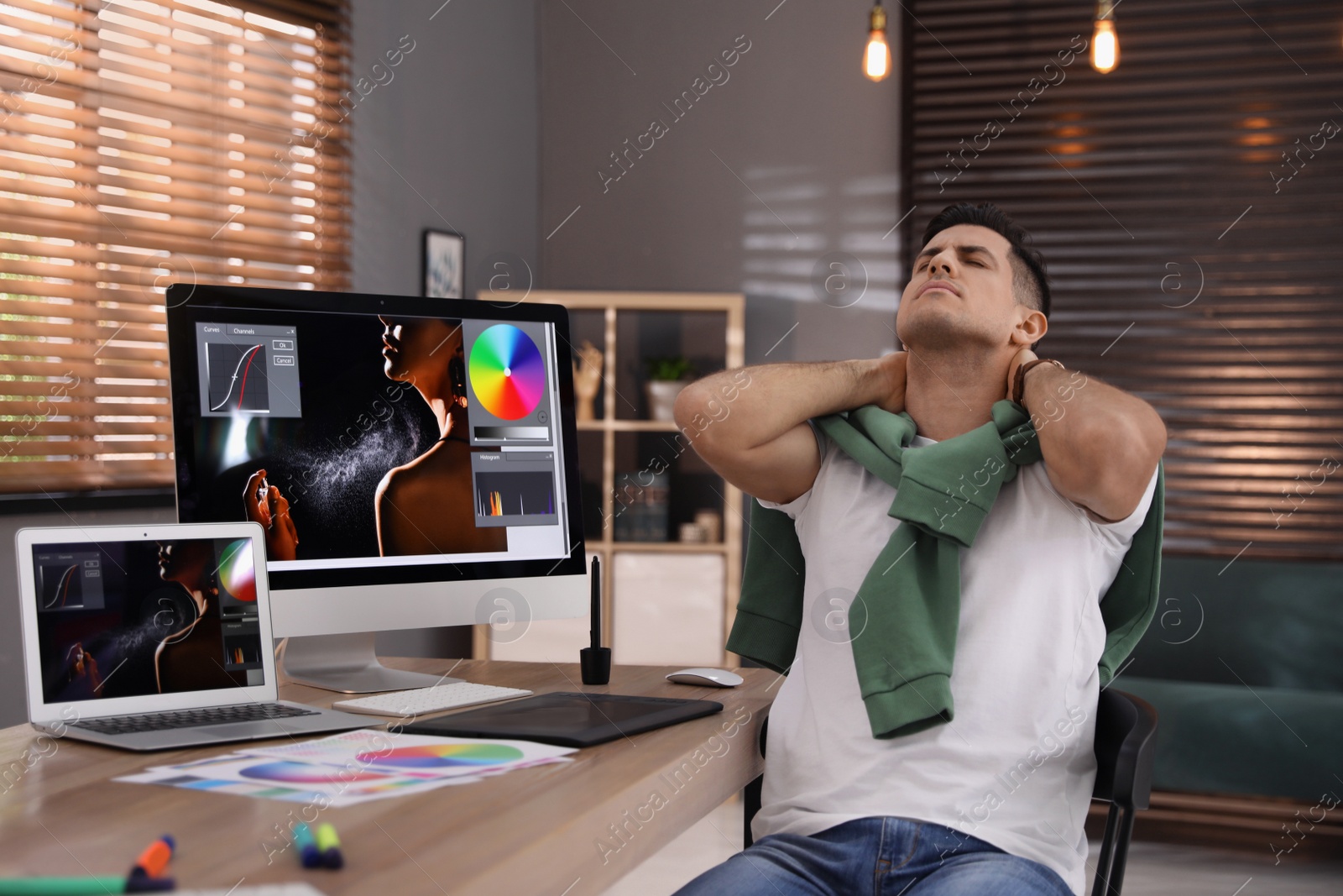 Photo of Tired retoucher at workplace with computer and laptop in office