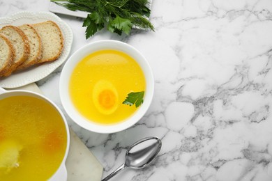 Photo of Delicious bouillon served on white marble table, flat lay. Space for text