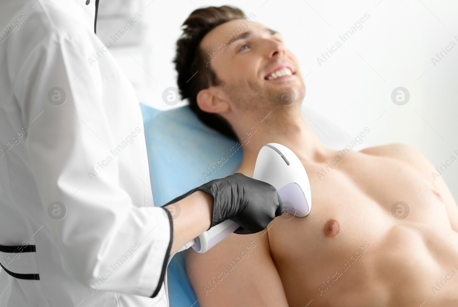 Photo of Man undergoing hair removal procedure with photo epilator in salon