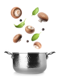 Fresh mushrooms, basil and peppercorns falling into pot on white background