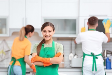 Photo of Team of professional janitors in uniform cleaning kitchen