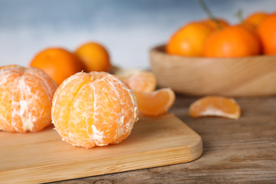 Photo of Peeled ripe tangerine on wooden table, closeup. Space for text