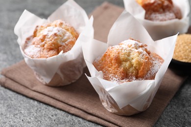 Photo of Delicious muffins with powdered sugar on grey table, closeup