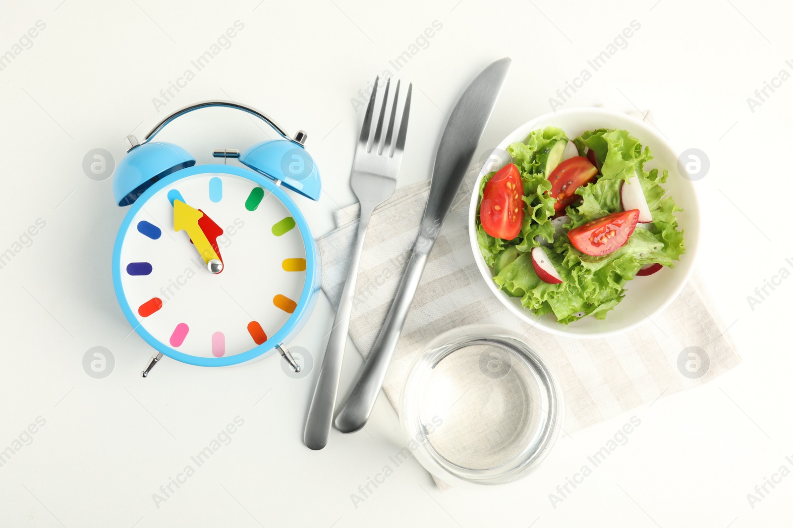 Photo of Alarm clock and salad on white background, top view. Meal timing concept